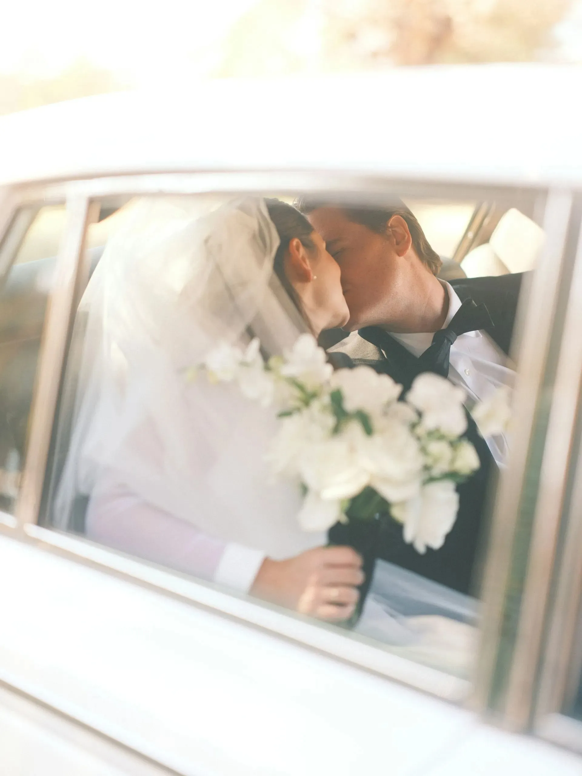 Newlyweds sharing a kiss in the back seat after their wedding shuttle service in Cleveland, OH